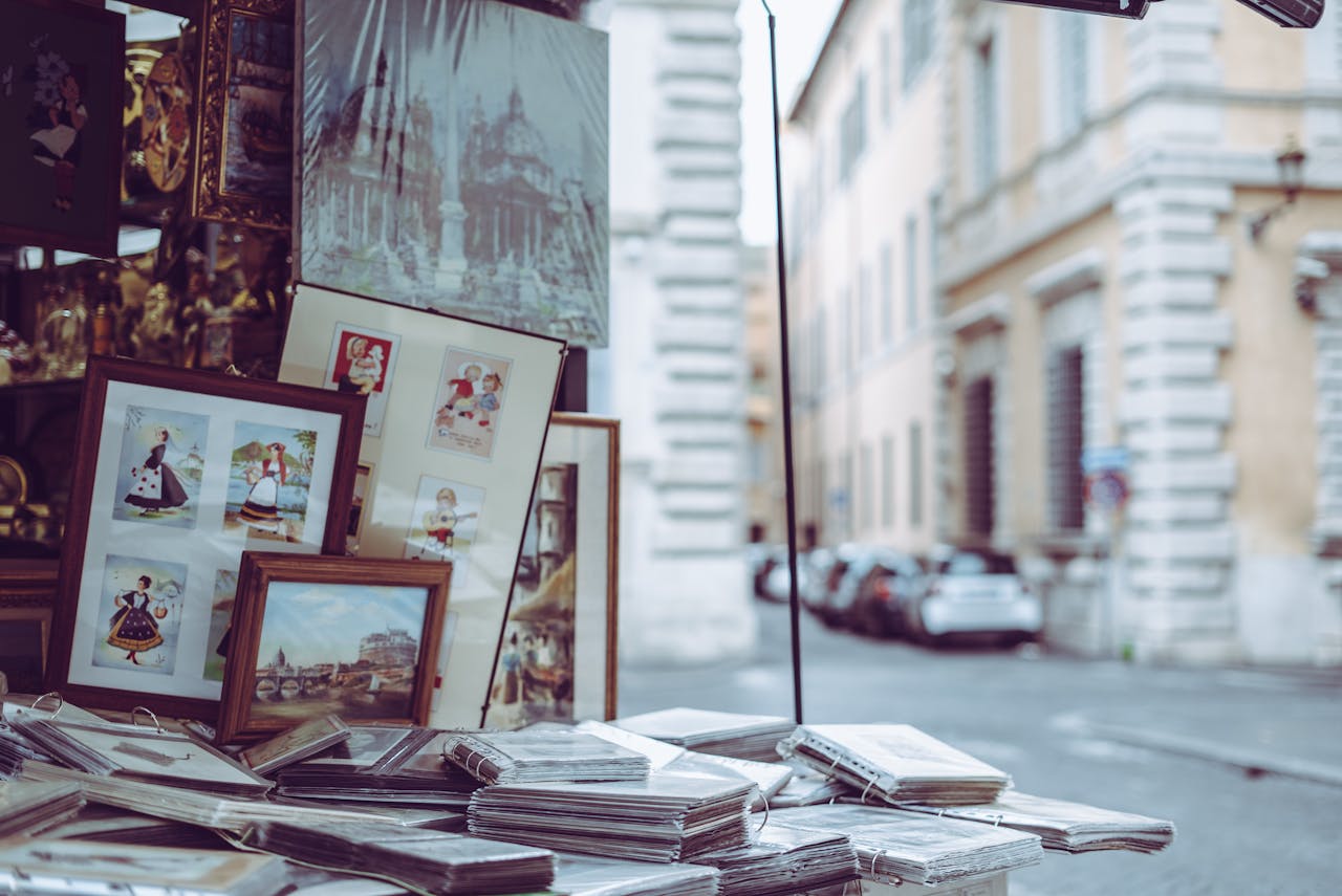 Framed art and pictures displayed at a street market in Rome, capturing the city's vibrant outdoor shopping scene.