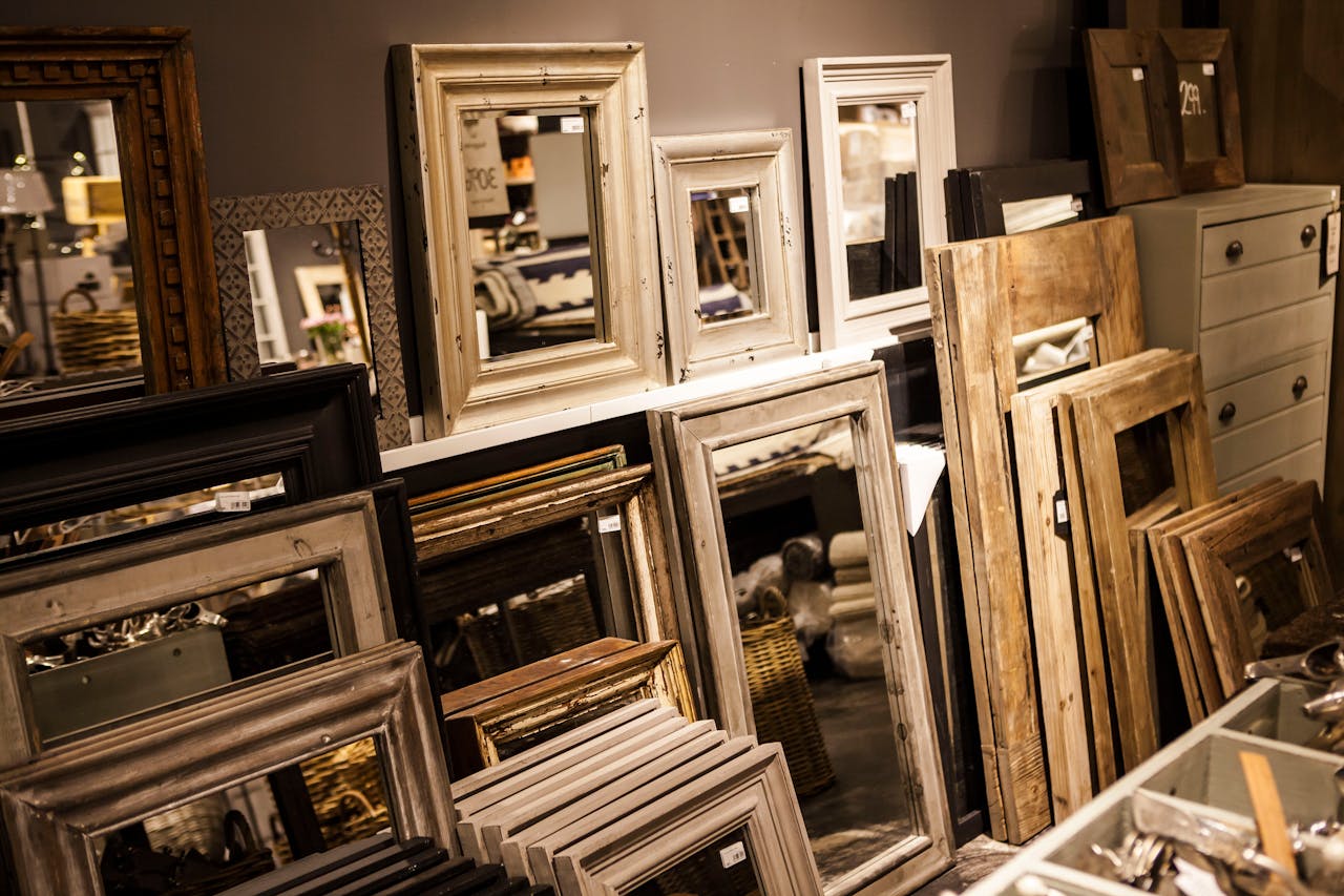 A collection of vintage-style mirror frames on display in a cozy interior shop setup.