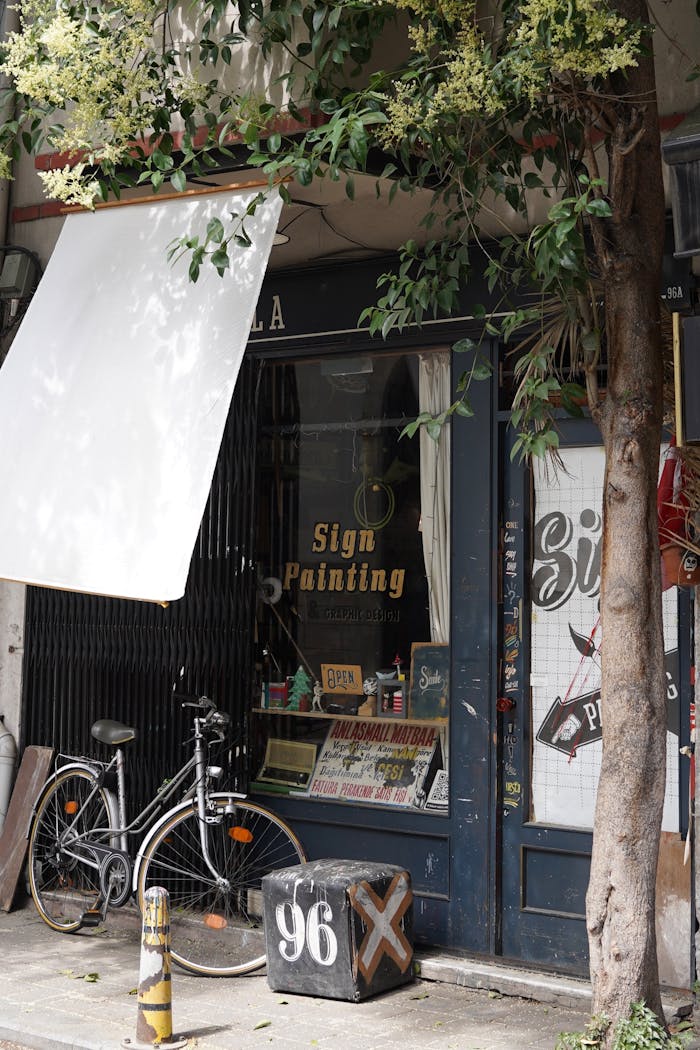 Charming vintage sign painting shop facade with bicycle parked outside.